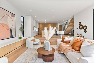 Modern living room with white sofa, wooden coffee table, and abstract art on wall.