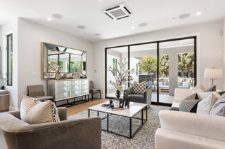Modern living room with gray sofa, white coffee table, and large windows.