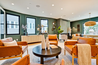 Modern living room with orange chairs, a round table, and decorative elements.