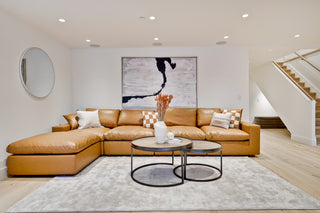 Modern living room with a brown sectional sofa, round coffee table, and decorative items.