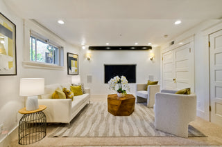 Modern living room with white chairs, black coffee table, and abstract art on the wall.