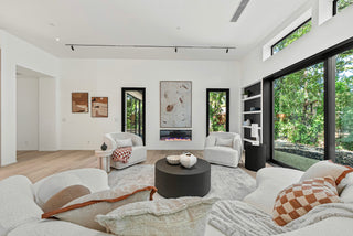 Modern living room with white furniture, a fireplace, and large windows and beautiful nature view