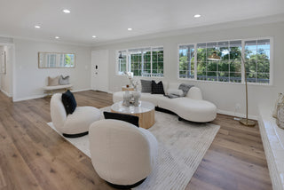 Modern living room with white furniture and large windows.