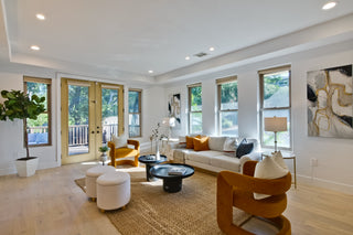 Modern living room with white sofa, wooden armchair, and decorative elements.