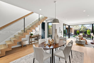 Modern living room with staircase, dining table, and chairs.