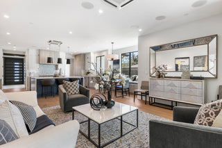 Modern living room with gray sofa, white coffee table, and decorative mirror.