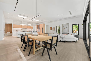Modern open-plan living room and kitchen with wooden dining table and chairs.
