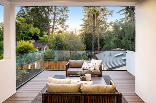 Modern outdoor Cutting-edge patio with wooden furniture and glass walls overlooking a forest.