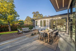 Modern outdoor patio with dining table, chairs, and a house in the background beautiful environment