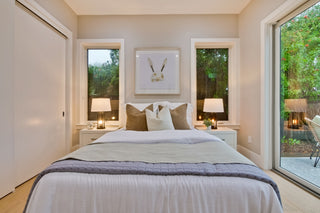 Neatly made bed in a bedroom with decorative pillows and lamps.