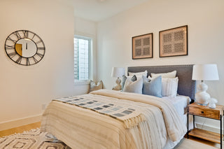 Neatly made bed in a bedroom with decorative pillows and stylish lamps 
