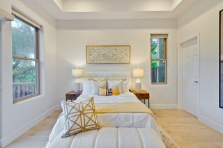 Neatly made bed in a bright bedroom with decorative pillows and lamps.