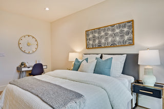 Neatly made bed with decorative pillows in a bedroom setting with watch
