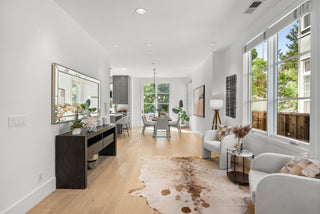 Modern living room with large windows, furniture, and decor.