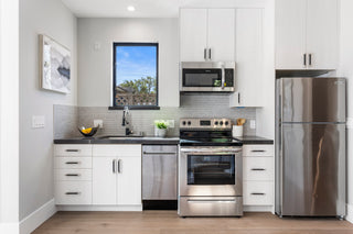 Modern kitchen with stainless steel appliances and white cabinets.