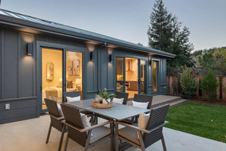 Outdoor patio area with a dining table and chairs in front of a modern house.