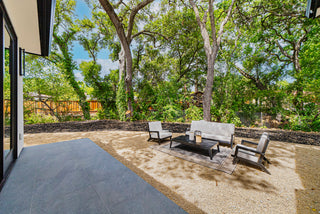 Outdoor patio area with furniture and trees in the background with sun light