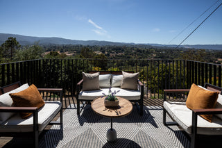 Outdoor patio furniture set with cushions on a balcony overlooking a scenic landscape.