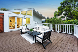 Outdoor patio with furniture and a view of a house and trees.