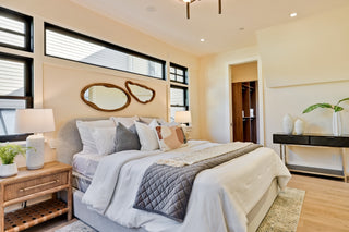 Modern bedroom with a bed, nightstands, and decorative mirrors.