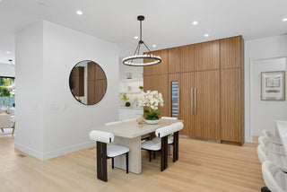 Modern dining room with wooden cabinets, white table, and chairs.
