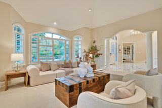 Modern living room with beige sofa, wooden coffee table, and large windows.