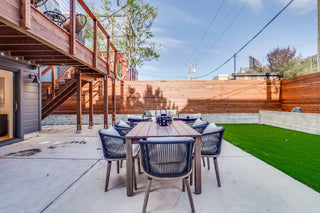 Outdoor patio with wooden dining table and chairs in a backyard setting.