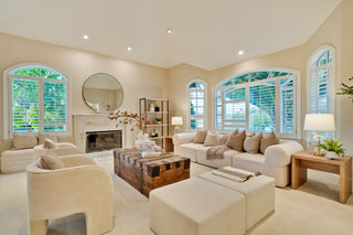 Modern living room with beige furniture, large windows, and decorative elements.