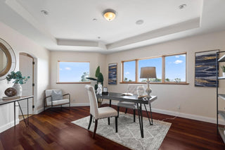 Spacious living room with large windows, wooden floors, and a cozy beige sofa. Blue rug and rustic coffee table enhance the modern, serene decor.