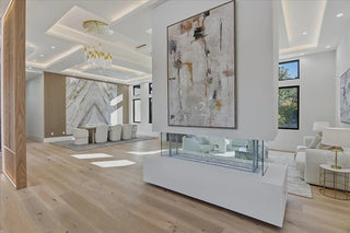 Modern living room with a fireplace, abstract art, and light wood flooring.