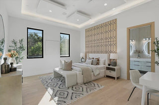 Stylish bedroom with white furniture, decorative pillows, and a patterned rug.