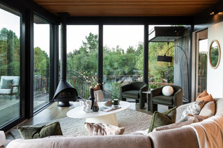 Modern living room with large windows, sofa, and decorative elements.