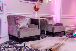 Two gray armchairs in a room with a cowhide rug and decorative elements.