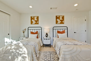 Two twin beds in a room with white walls, nightstands, and decorative pillows.