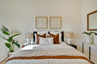 Neatly made bed with decorative pillows in a bedroom setting.