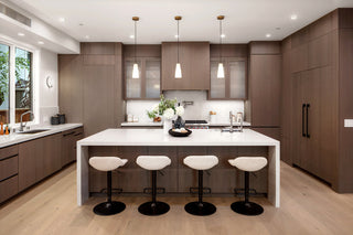 Modern kitchen with wooden cabinets, white island, and bar stools.
