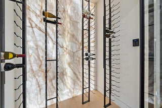 Wine rack system with  wine bottles against a marble wall