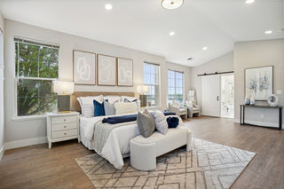 Modern bedroom with white furniture, large windows, and decorative elements.