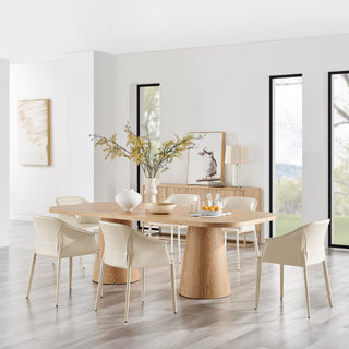 Modern light wood dining table with cream chairs and floral centerpiece in bright, stylish interior.
