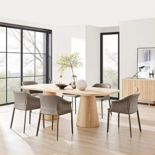 Modern dining room with a wooden table and gray leather chairs, featuring a stylish vase and decor.