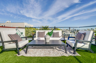 Outdoor patio set with chairs, table, and cushions on a grassy rooftop with cityscape in the background.