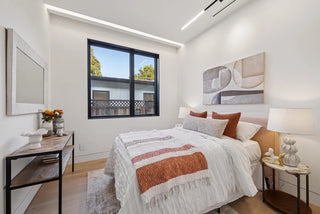 cozy and soft  bedroom with a bed, side tables, and artwork on the wall.