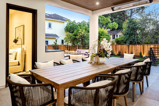  cozy chairs with patterned cushions, and a long fire pit table. Warm lighting and wooden fencing create a welcoming ambiance new design patio with a sleek grill,