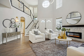 Modern living room with white furniture, decorative elements, and a staircase.