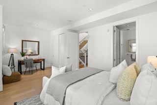 Modern bedroom with a bed, desk, and staircase in the background