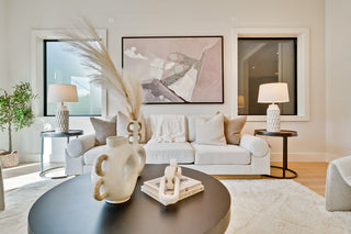 Modern living room with a white sofa, decorative items on a coffee table, and abstract art on the wall.
