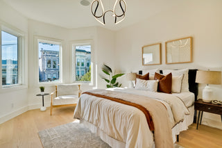 Modern bedroom with a bed, lamps, and large windows.
