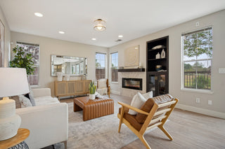 Modern living room with white sofa, wooden armchair, and fireplace.